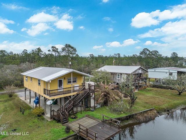 rear view of property featuring stairs, a lawn, and a water view