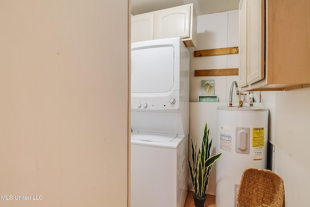 washroom featuring stacked washer / drying machine, water heater, and cabinet space