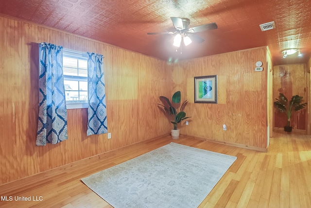 exercise area featuring an ornate ceiling, visible vents, wooden walls, and hardwood / wood-style flooring