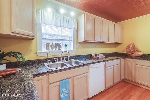 kitchen featuring crown molding, light wood-style flooring, a sink, dark stone countertops, and dishwasher