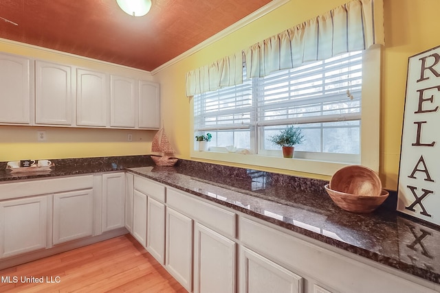 kitchen featuring ornamental molding, dark stone countertops, and white cabinets