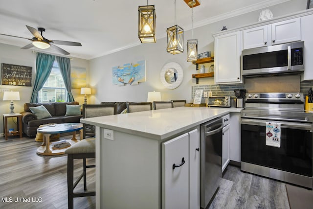 kitchen featuring a kitchen breakfast bar, appliances with stainless steel finishes, kitchen peninsula, and white cabinetry