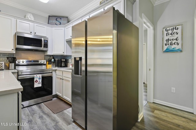 kitchen featuring ornamental molding, white cabinets, stainless steel appliances, and backsplash