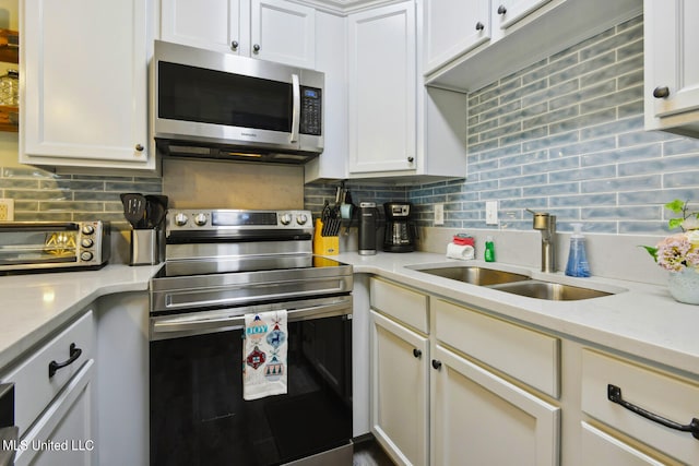 kitchen with tasteful backsplash, sink, stainless steel appliances, white cabinets, and light stone counters