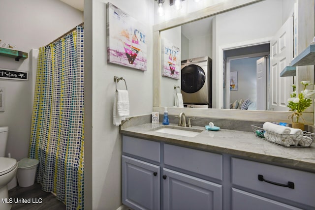 bathroom with vanity, toilet, hardwood / wood-style flooring, and stacked washer and clothes dryer