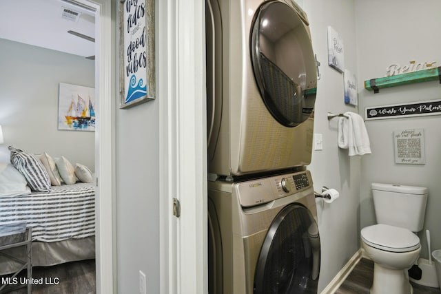 clothes washing area with stacked washer and dryer and hardwood / wood-style floors