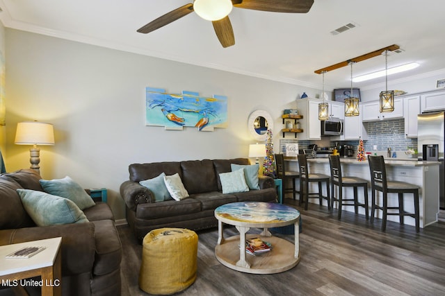 living room with crown molding, dark wood-type flooring, and ceiling fan