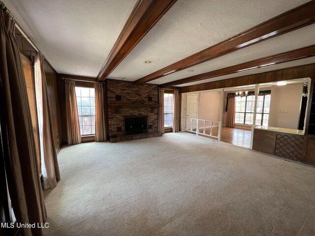 unfurnished living room with light carpet, a textured ceiling, and a wealth of natural light