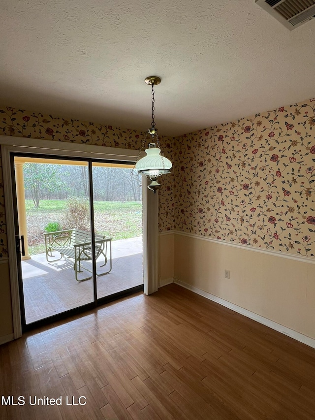 unfurnished dining area with a textured ceiling and wood-type flooring