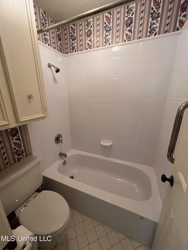 bathroom with a textured ceiling, toilet, and shower / bath combination