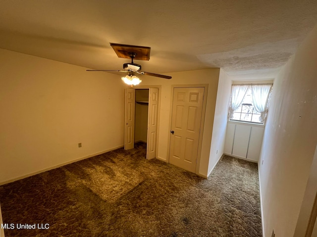 unfurnished bedroom featuring dark carpet, a textured ceiling, and ceiling fan