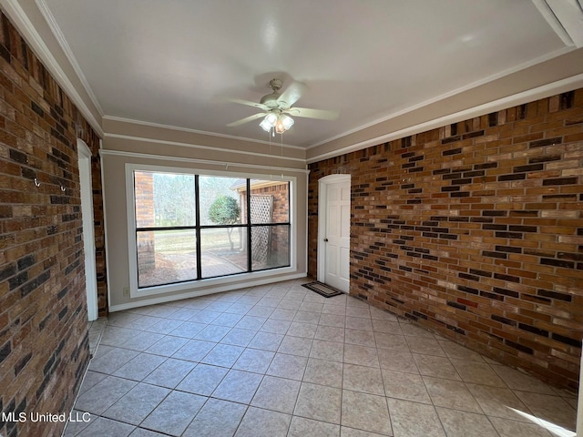 tiled spare room with ornamental molding, brick wall, and ceiling fan