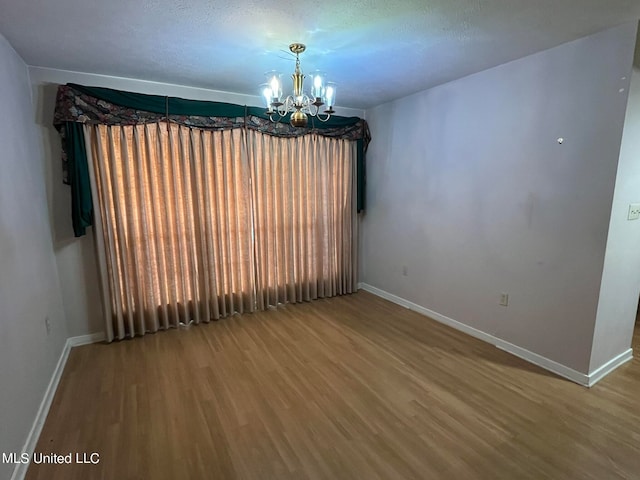 unfurnished dining area featuring an inviting chandelier, a textured ceiling, and wood-type flooring