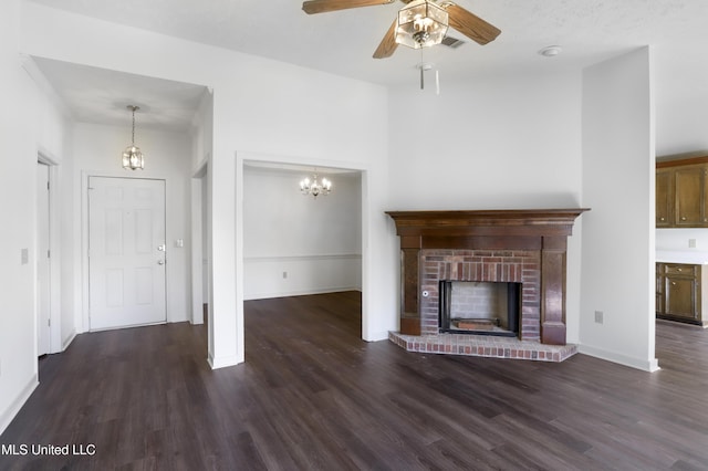 unfurnished living room with a brick fireplace, dark hardwood / wood-style flooring, and ceiling fan with notable chandelier