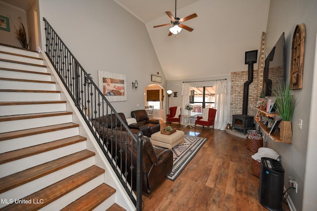 living room featuring a wood stove, high vaulted ceiling, ceiling fan, and wood-type flooring