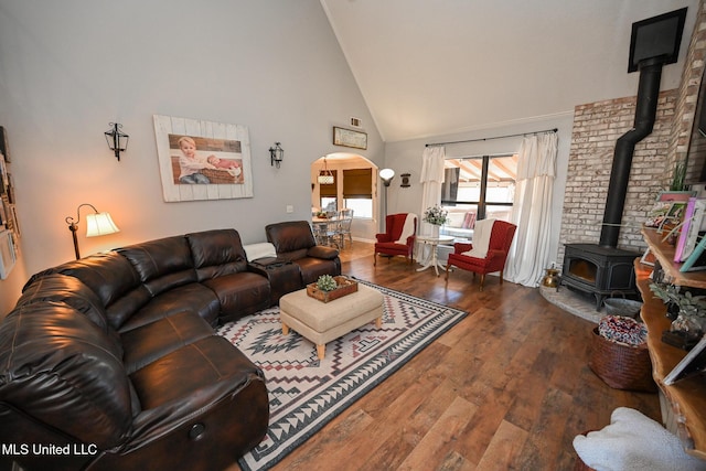 living room featuring dark wood-type flooring, high vaulted ceiling, and a wood stove