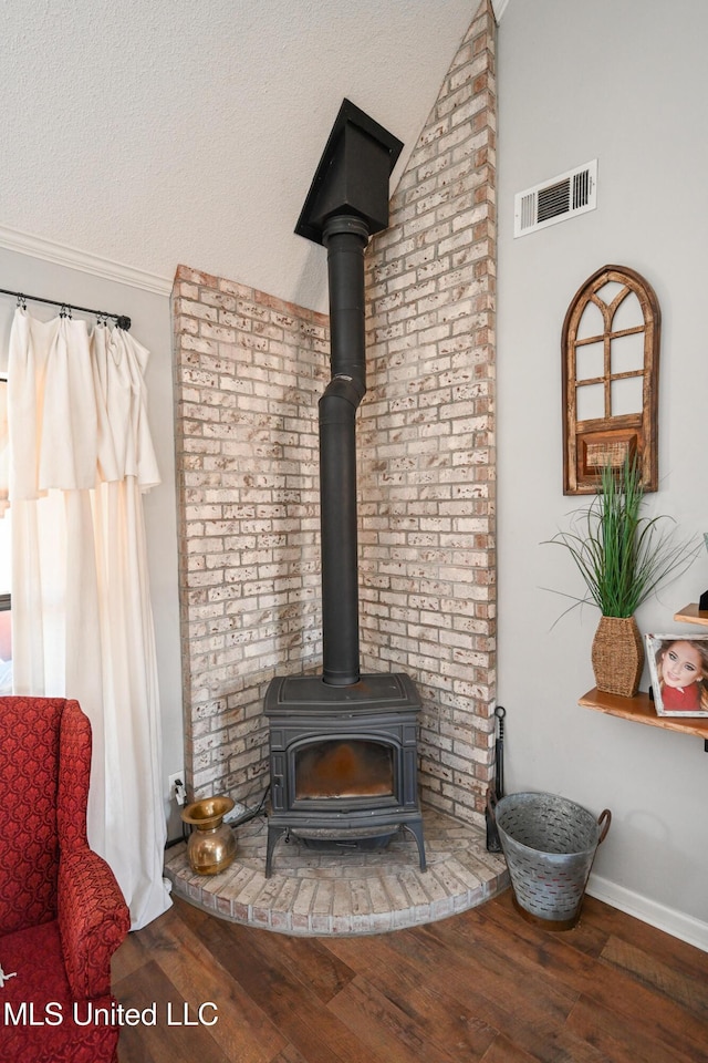 room details with a textured ceiling, a wood stove, and hardwood / wood-style floors