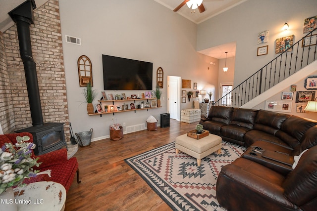 living room featuring a high ceiling, ceiling fan, ornamental molding, and wood-type flooring