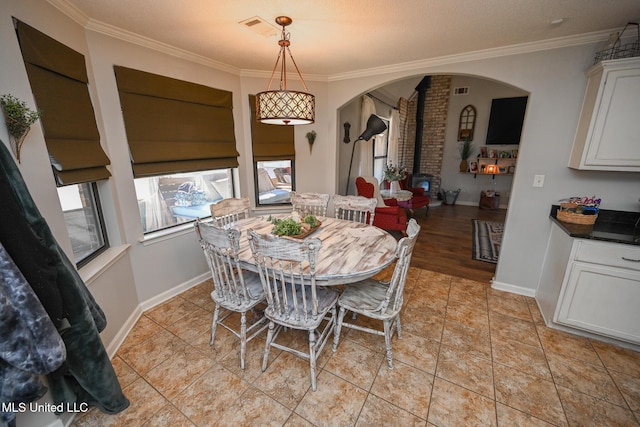 dining room with a textured ceiling, light tile patterned floors, and crown molding