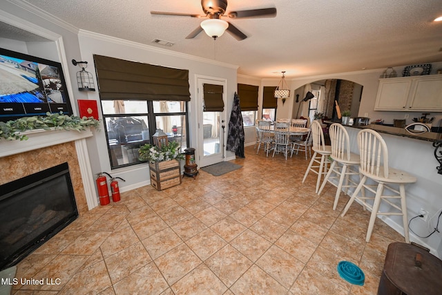 interior space featuring a textured ceiling, ceiling fan, crown molding, and light tile patterned floors