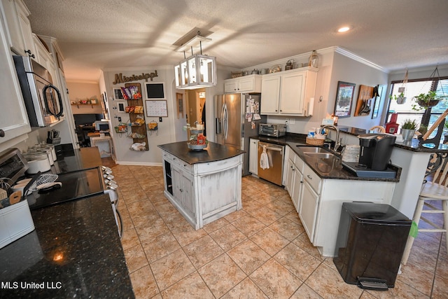 kitchen featuring stainless steel appliances, pendant lighting, a kitchen island, sink, and white cabinetry