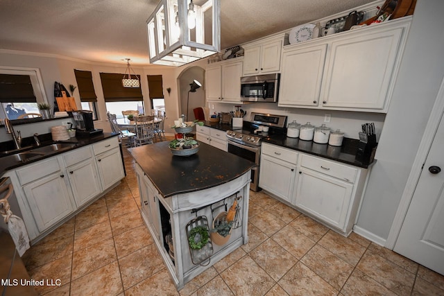 kitchen with a textured ceiling, appliances with stainless steel finishes, white cabinetry, and sink