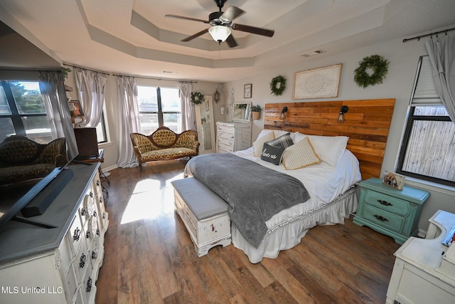 bedroom with ceiling fan, a raised ceiling, and dark hardwood / wood-style floors