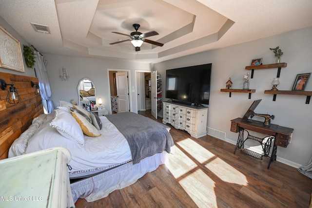 bedroom featuring ceiling fan, a tray ceiling, and dark hardwood / wood-style floors