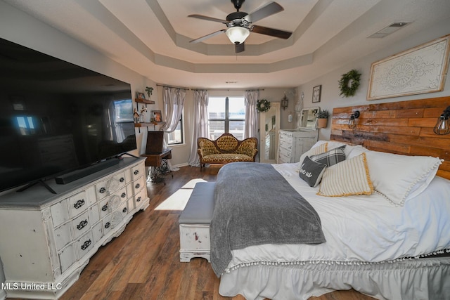 bedroom with ceiling fan, dark wood-type flooring, and a raised ceiling