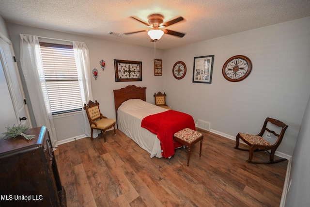 bedroom with a textured ceiling, ceiling fan, and hardwood / wood-style floors