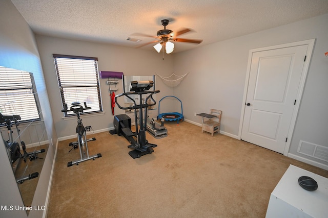 exercise area with a textured ceiling, ceiling fan, and light colored carpet