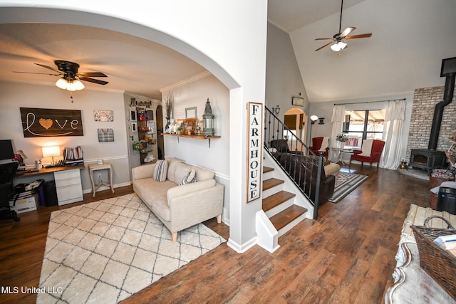 living room with ceiling fan, hardwood / wood-style floors, vaulted ceiling, and a wood stove