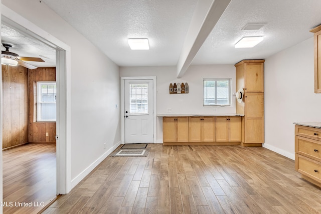 kitchen with light brown cabinetry, wooden walls, light hardwood / wood-style floors, and ceiling fan