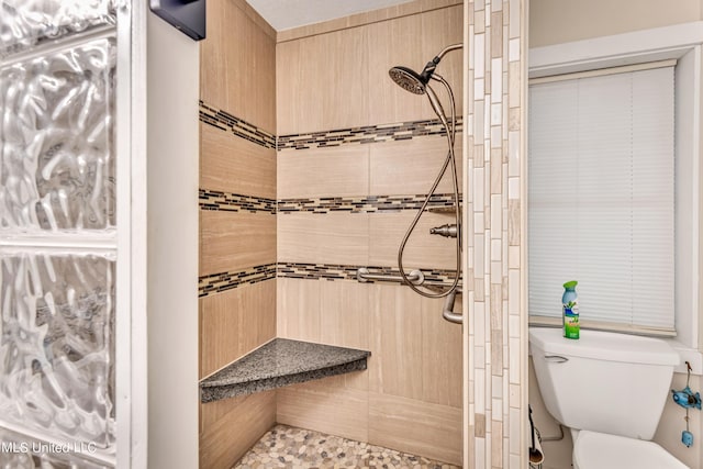 bathroom with a tile shower and toilet