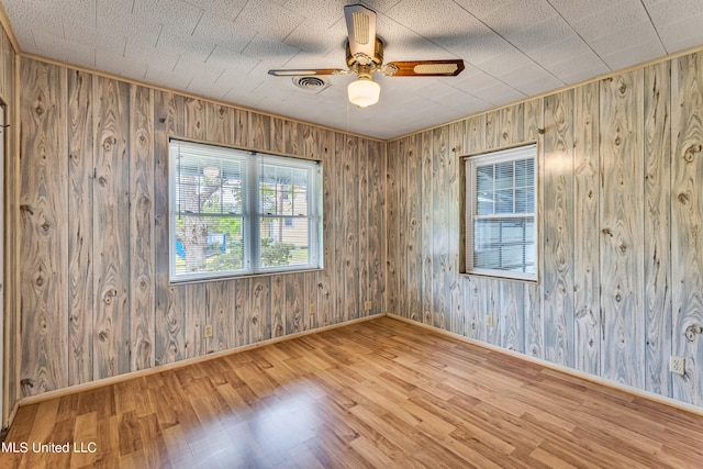 spare room with ceiling fan, hardwood / wood-style flooring, and wood walls