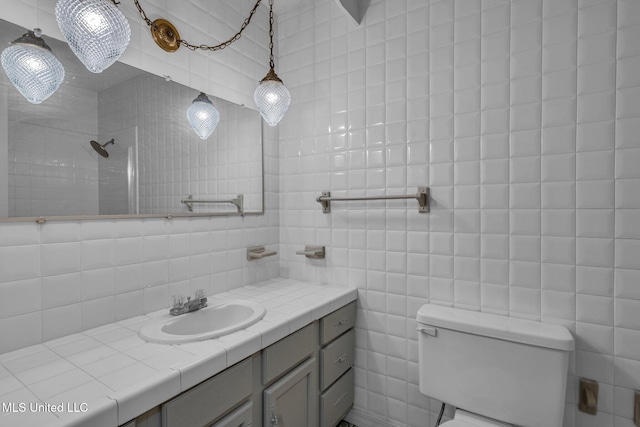 bathroom with backsplash, a tile shower, tile walls, toilet, and vanity