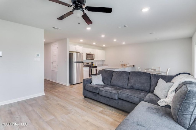living room featuring recessed lighting, a ceiling fan, visible vents, and light wood-style flooring