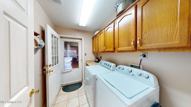 laundry area with independent washer and dryer, cabinets, light tile patterned floors, and a textured ceiling