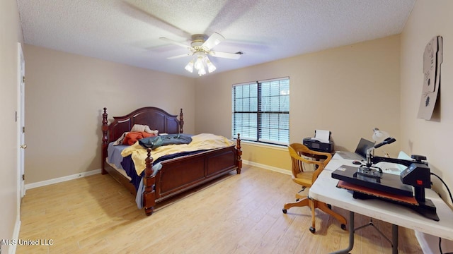 bedroom featuring ceiling fan, light wood-type flooring, and a textured ceiling