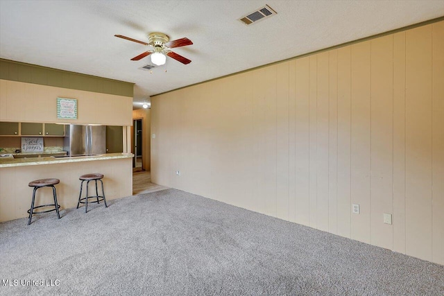 unfurnished living room with light colored carpet, a textured ceiling, and ceiling fan