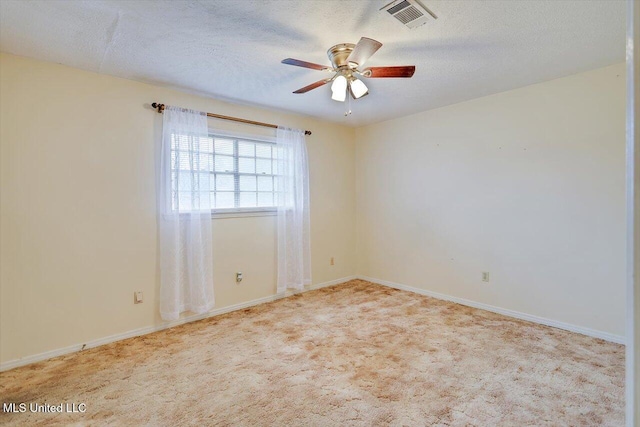 spare room with light carpet, ceiling fan, and a textured ceiling