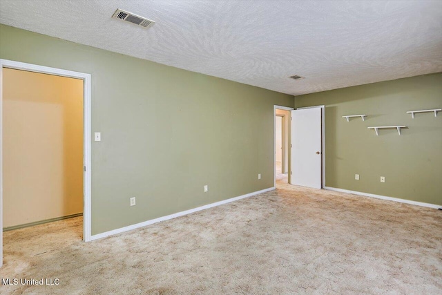 unfurnished room with light colored carpet and a textured ceiling