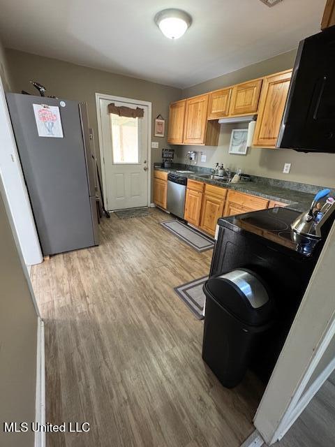 kitchen with appliances with stainless steel finishes, sink, and light hardwood / wood-style flooring