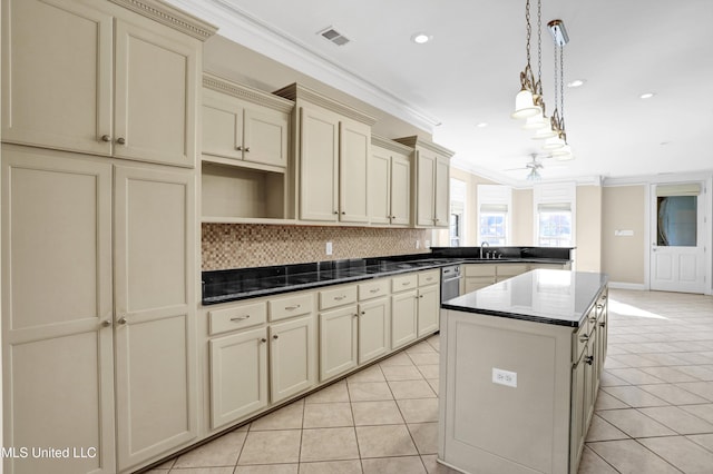 kitchen with a kitchen island, decorative light fixtures, cream cabinets, light tile patterned floors, and crown molding