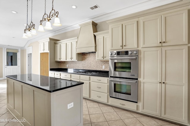 kitchen featuring custom exhaust hood, hanging light fixtures, appliances with stainless steel finishes, ornamental molding, and cream cabinetry