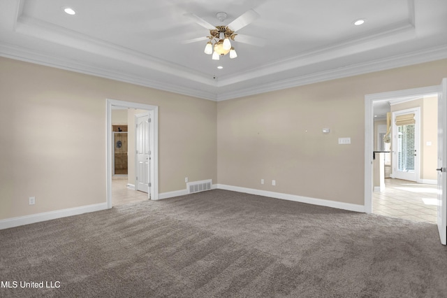 carpeted spare room featuring ceiling fan, ornamental molding, and a raised ceiling