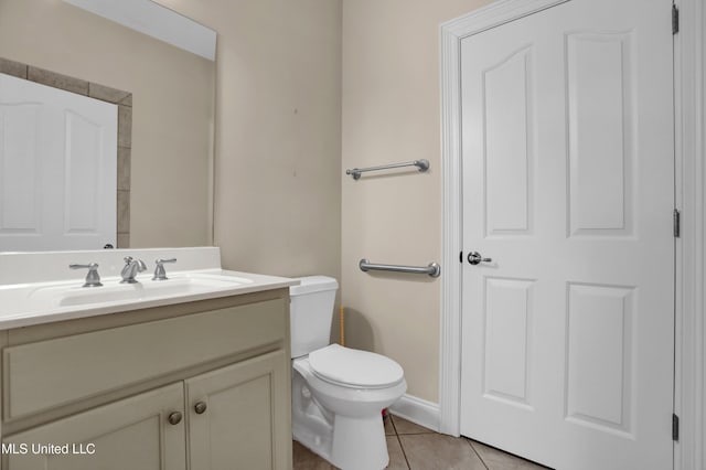 bathroom with toilet, vanity, and tile patterned flooring