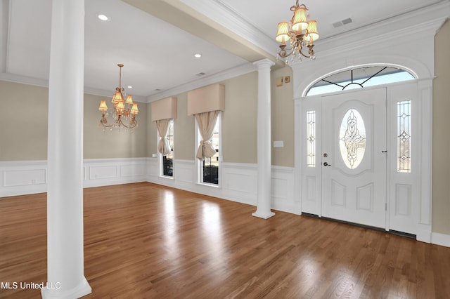 entryway with ornate columns, crown molding, and a notable chandelier