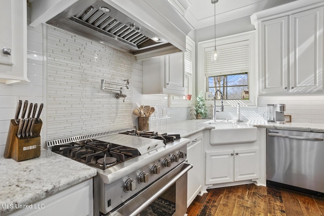 kitchen with sink, appliances with stainless steel finishes, custom range hood, white cabinets, and decorative light fixtures