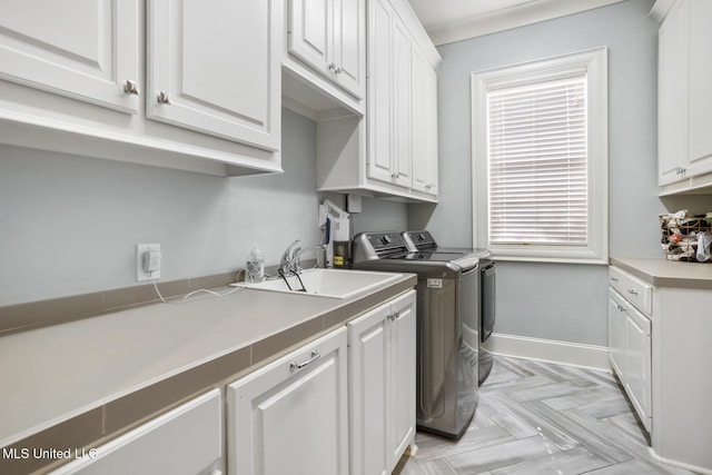 washroom featuring sink, light parquet flooring, cabinets, and independent washer and dryer